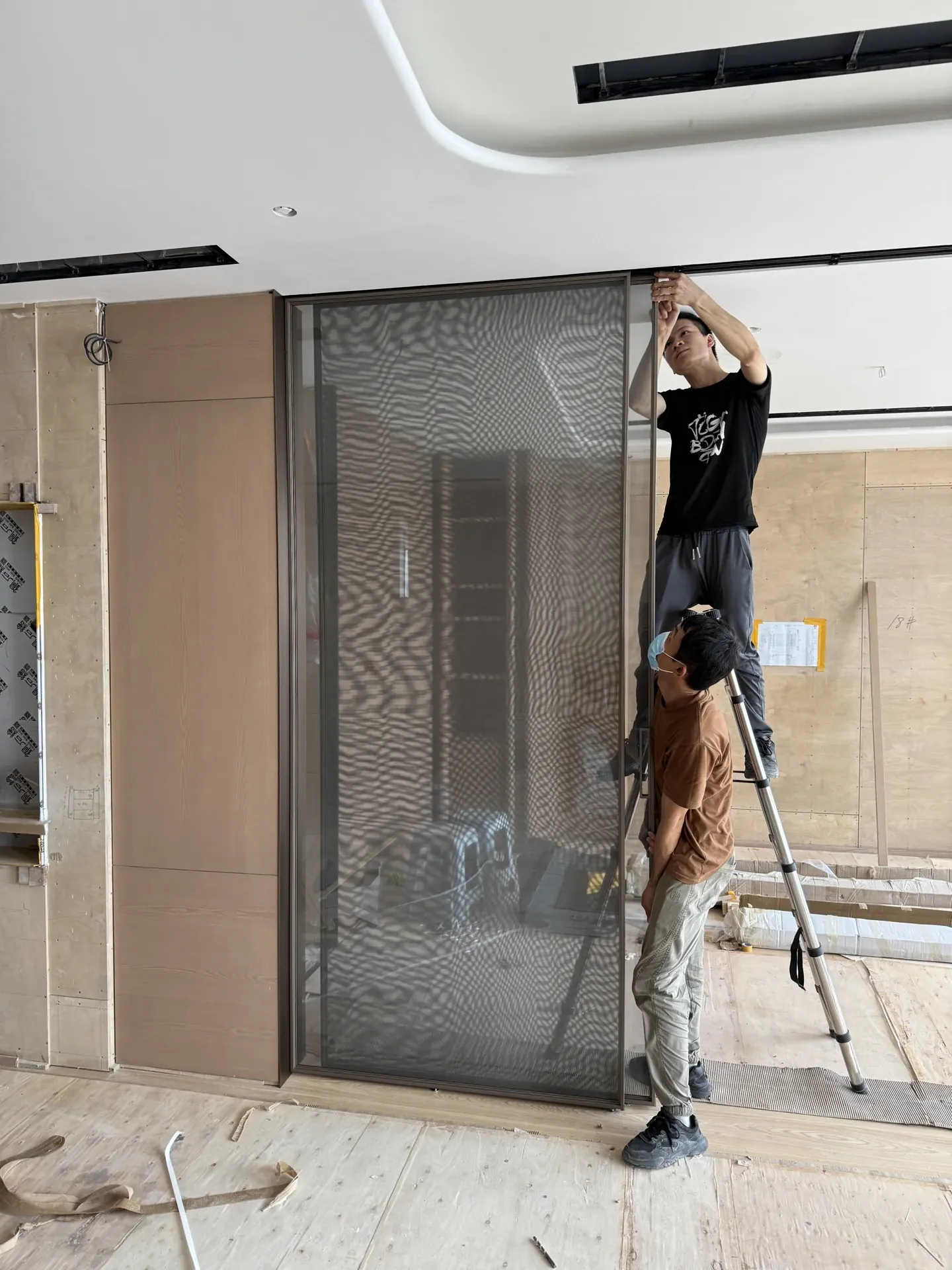 Two installers positioning and fitting a tall framed interior door on site